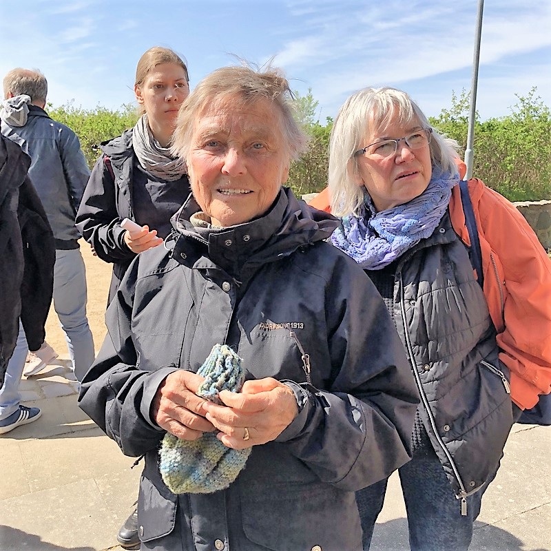 In the center of the picture you see Kaethe Birkenfeldt who, at age 12, saw Nazis dump ammunition from the evacuating train of Muna Lübberstedt into Lake Dieksee, Timmdorf. She is holding a woolen hat in her hands. She looks much younger than 86. In the background you see two women looking to something going on left of the photographer.
