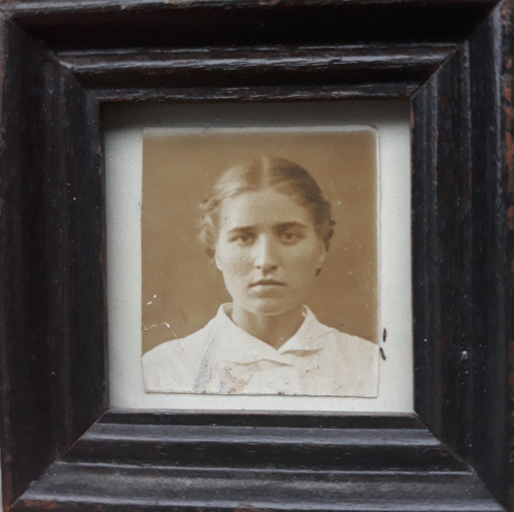 Portrait von Großmutter Nina. Sie trägt eine weiße, hochgeknöpfte Bluse. Die Haare in der Mitte gescheitelt und im Nacken zusammengesteckt.